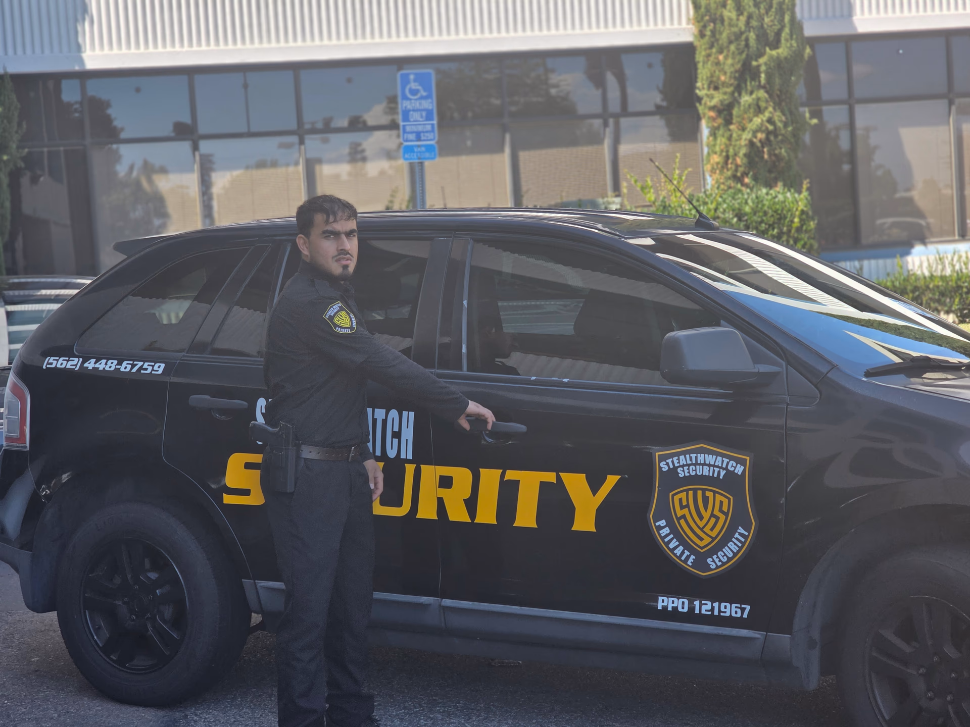 Stealth Watch Security guards standing by a branded patrol vehicle at a commercial property.